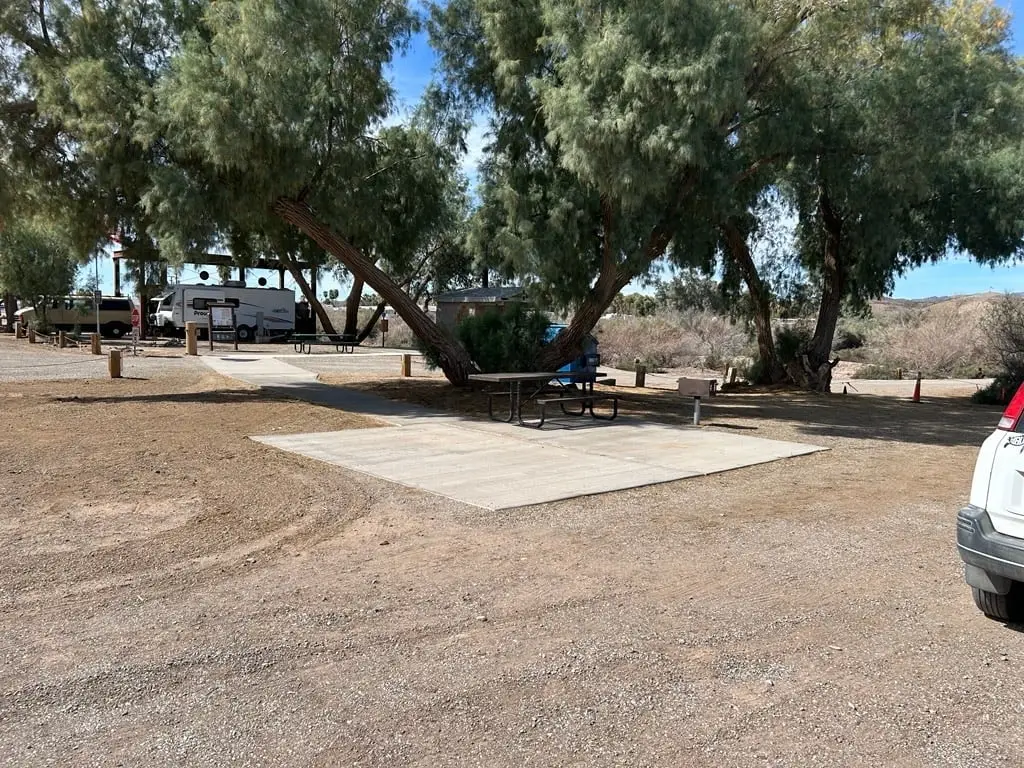 A poured concrete pad on a gravel campsite with RVs parked in the background