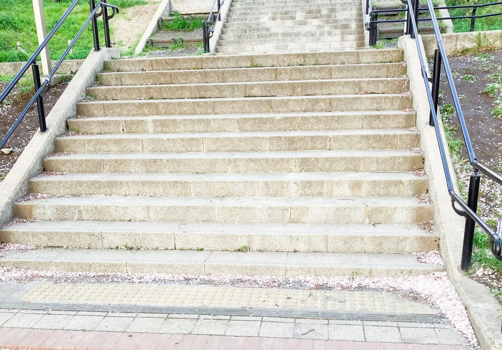 Wide set of outdoor concrete steps with black metal handrails on both sides